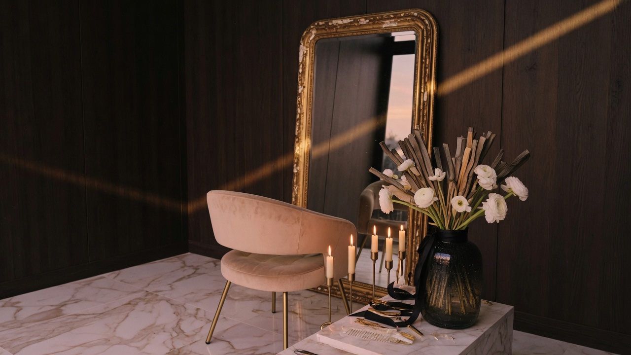 Atelier con espejo de oro, silla de terciopelo y ranúnculos blancos.
